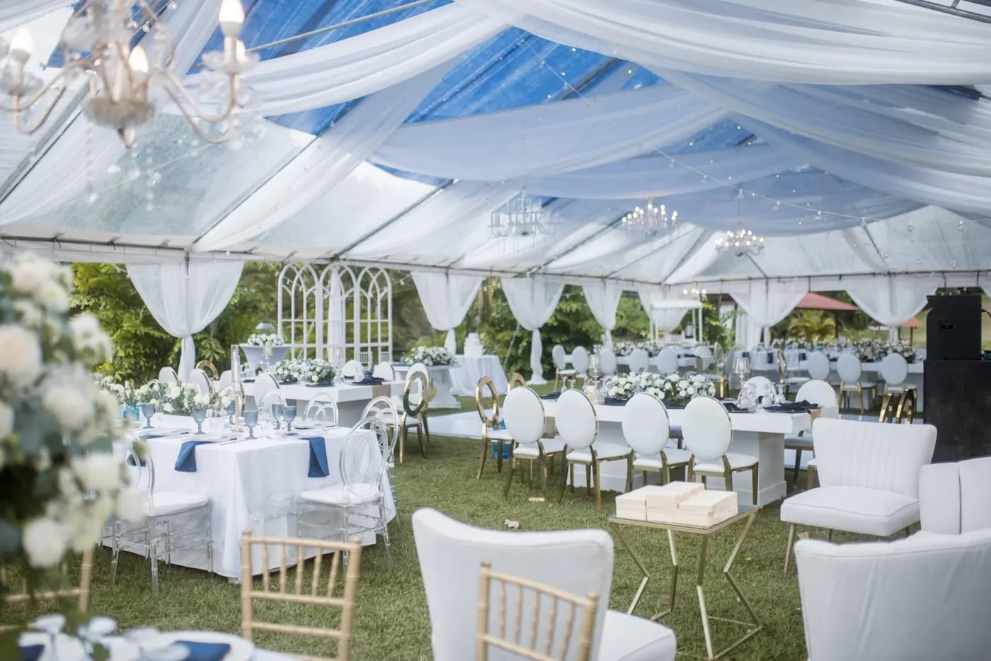Salón de boda con sillas doradas, drapeados blancos e iluminación cálida